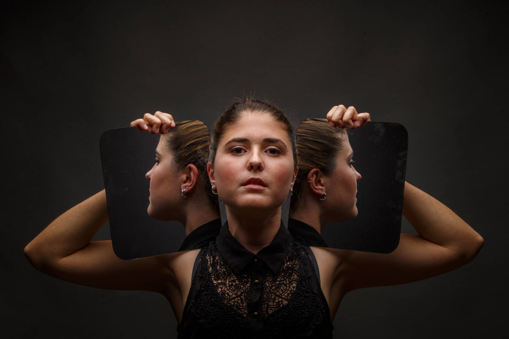 Modern model holding mirrors on sides of face