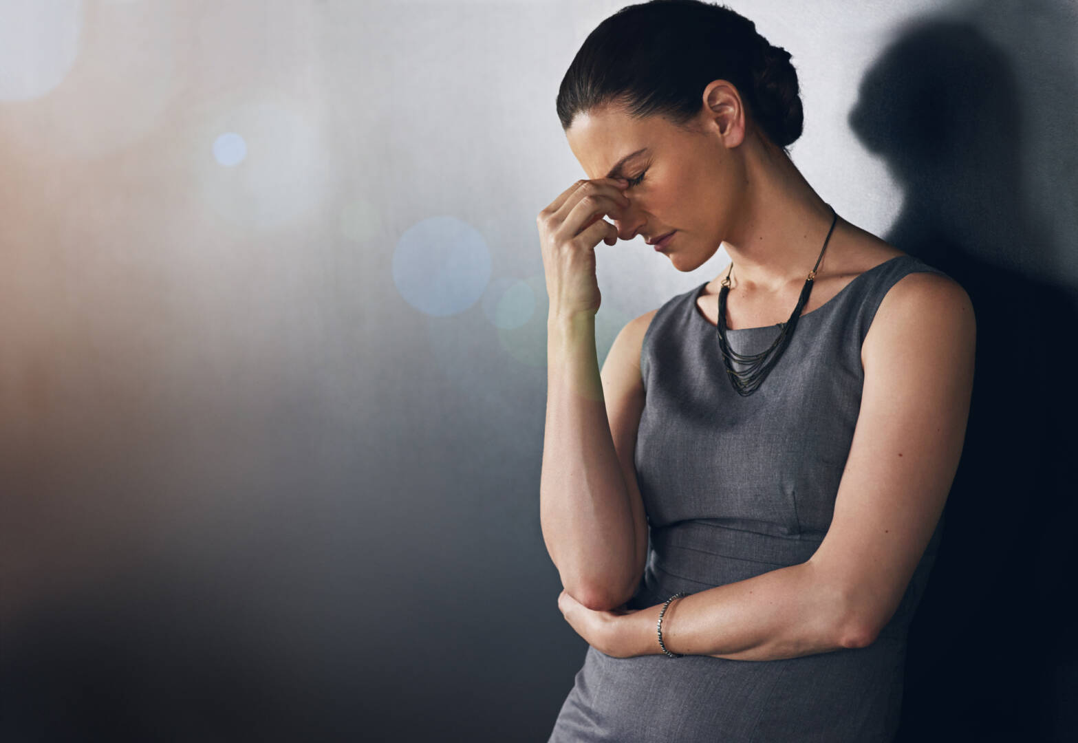 Studio shot of a businesswoman looking stressed out against a grey background.